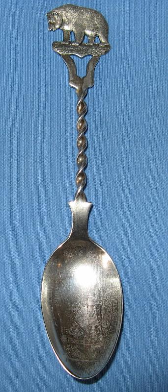 River Hill Mine Placerville, CA.JPG - SOUVENIR MINING SPOON RIVER HILL MINE PLACERVILLE CALIFORNIA - Sterling silver souvenir spoon, lightly engraved in bowl above engraved depiction of mine and structures RIVER HILL MINE and below PLACERVILLE, CAL., handle finial has California golden bear image with a helical screw shaped handle, sterling mark on reverse, 5 7/8 in. long, 21.9 grams (Placerville is the county seat of California’s El Dorado County.  The town played a key role as the central hub for the Mother Lode region’s mining operations.  After the discovery of gold by James W. Marshall in 1848 in nearby Coloma, California some eight miles north of Placerville, the small town of Placerville was known as Dry Diggins after the manner in which the miners moved cartloads of dry soil to running water to separate the gold from the soil. With the Gold Rush riches came problems and later in 1849, the town earned its more common historical name, Hangtown, because of the numerous hangings that occurred there.  In 1854 the town’s name was changed to a friendlier-sounding Placerville and the town was incorporated.  At the time of incorporation, Placerville was the third largest city in California, a testament to the town’s importance to the development of the Mother Lode with its many services, transportation of goods and people, lodging, banking, market and general store.  The Placerville District includes the placer deposits here and in the adjacent Smith Flat, Diamond Springs, Texas Hill, Coon Hollow, and White Rock areas as well as the lode mines of the Mother Lode belt.  The lode-gold deposits are massive quartz veins as much as 20 feet thick with numerous parallel stringers. The ore bodies are low to moderate in grade (1/7 to 1/4 ounce of gold per ton), but the veins have been mined to depths of 2000 feet. The ore contains finely disseminated free gold and small amounts of pyrite. The veins occur chiefly in slate.  The River Hill group of mines, which included the Bell, Gentle Annie, Ball Consolidated, Lucky Star, Lyon and New Era, was located on 178 acres of the Mother Lode, one and one-half miles northwest of Placerville.  Originally worked around 1865 and then from 1890 to 1906, these mines were very rich, and produced quite a large amount of gold. Five parallel veins, with ore shoots up to twenty feet in width and 150 feet in length, were developed by 1550-foot and 600-foot inclined shafts, a 2400-foot adit and much drifting. The ore was originally treated in a ten-stamp mill, which was replaced with a twenty-stamp mill in 1901. The Placerville lode mining operations pretty much ceased activity by about 1915.)
